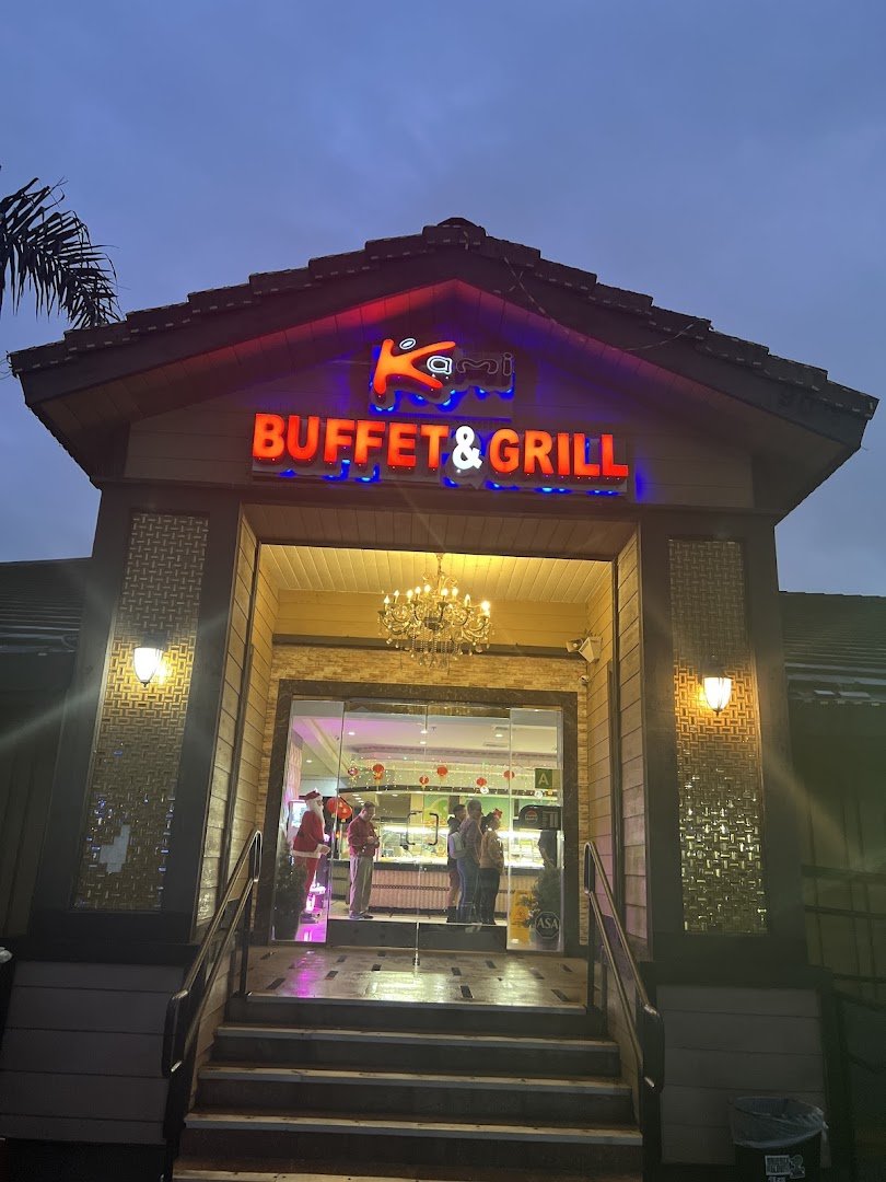 Busy buffet line with trays of Asian fusion dishes.